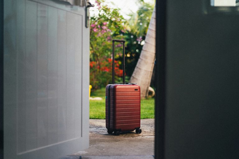 How to Cope when is out of town - Red suitcase sitting outside door