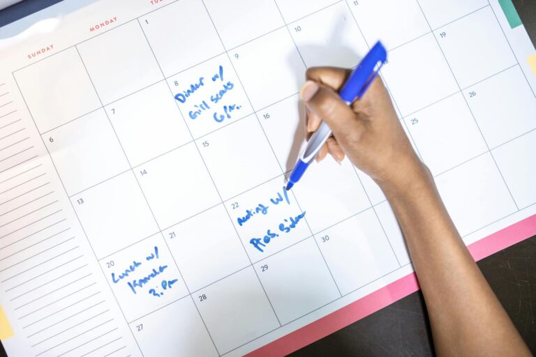 Woman writing on large family schedule calendar