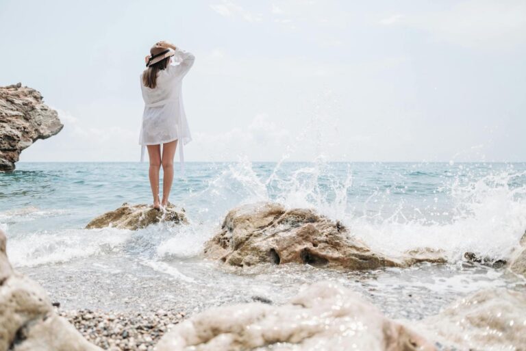 Women standing on rock in ocean trusting God