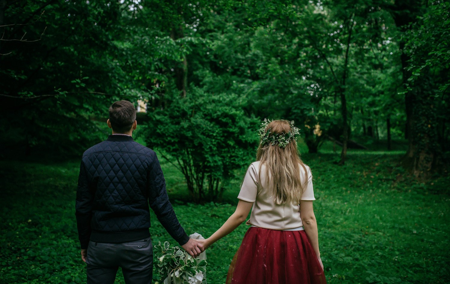 man and woman holding hands in forest