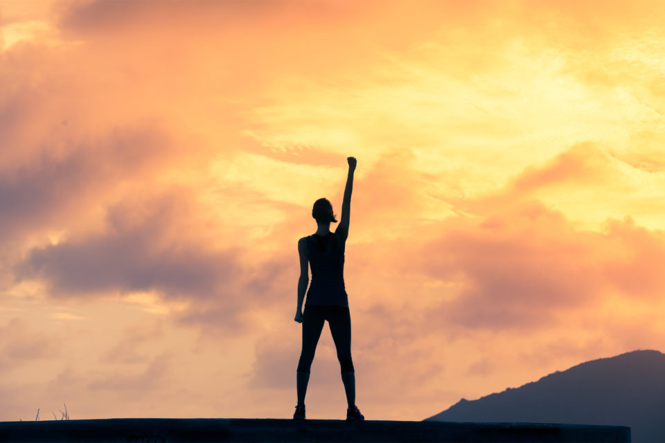 Woman with confidence standing on mountain overcoming insecurity