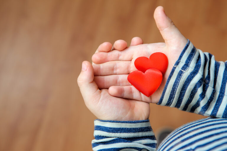 Child holding two red hearts in their hand
