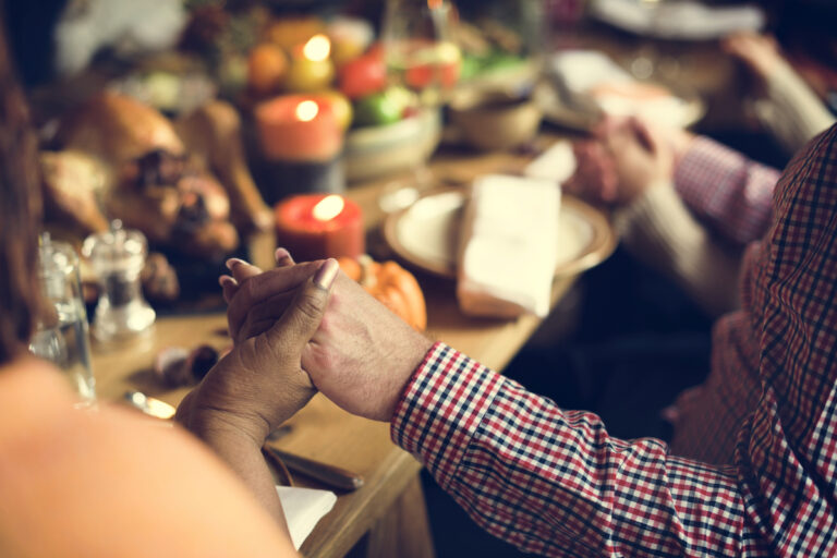 People holding hands around the thanksgiving table showing gratitude