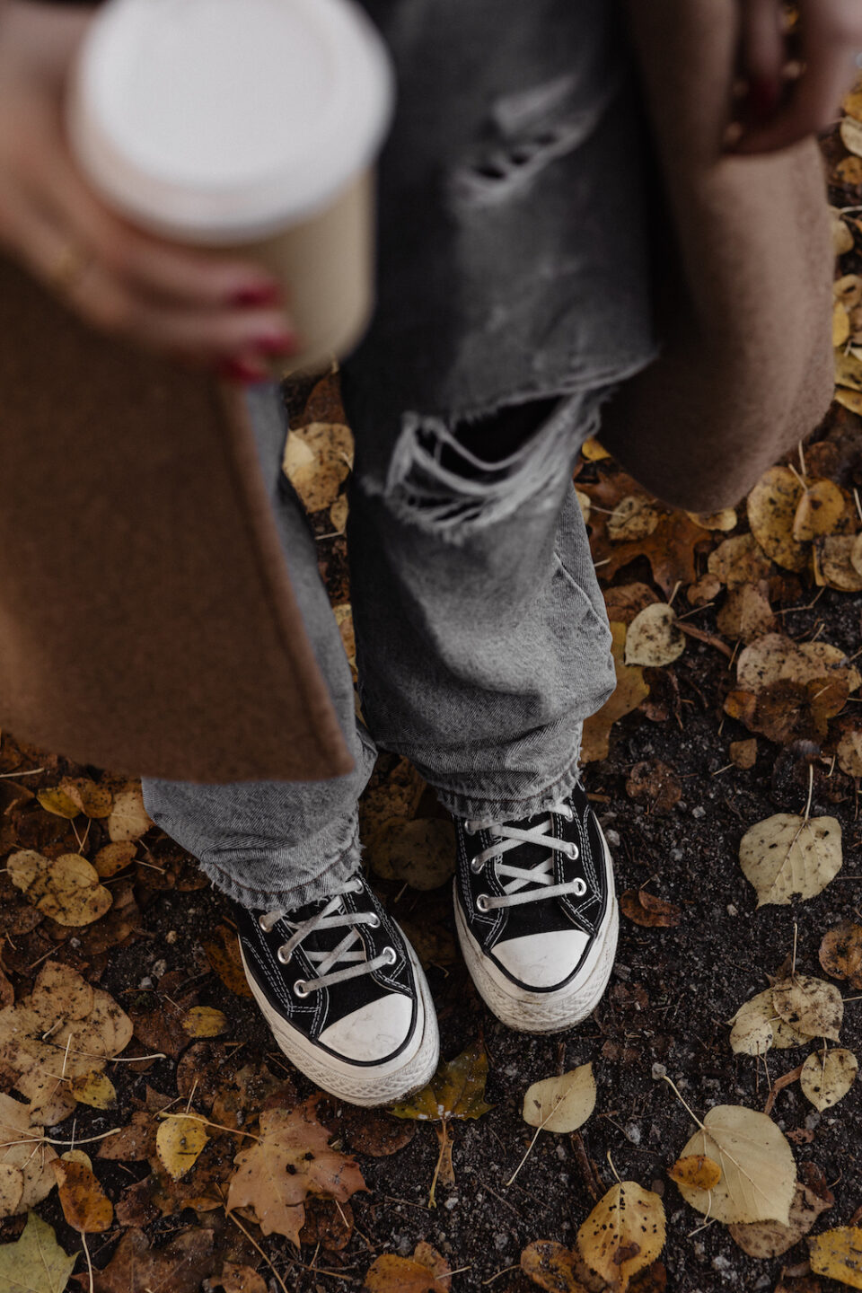 Woman holding coffee standing in leaves