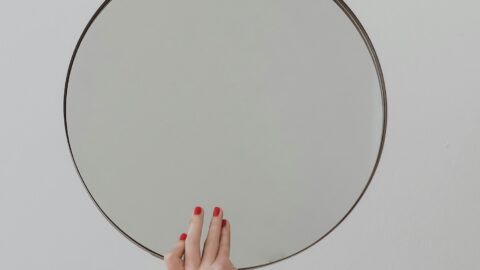 Womens hand with red nails holding a mirror
