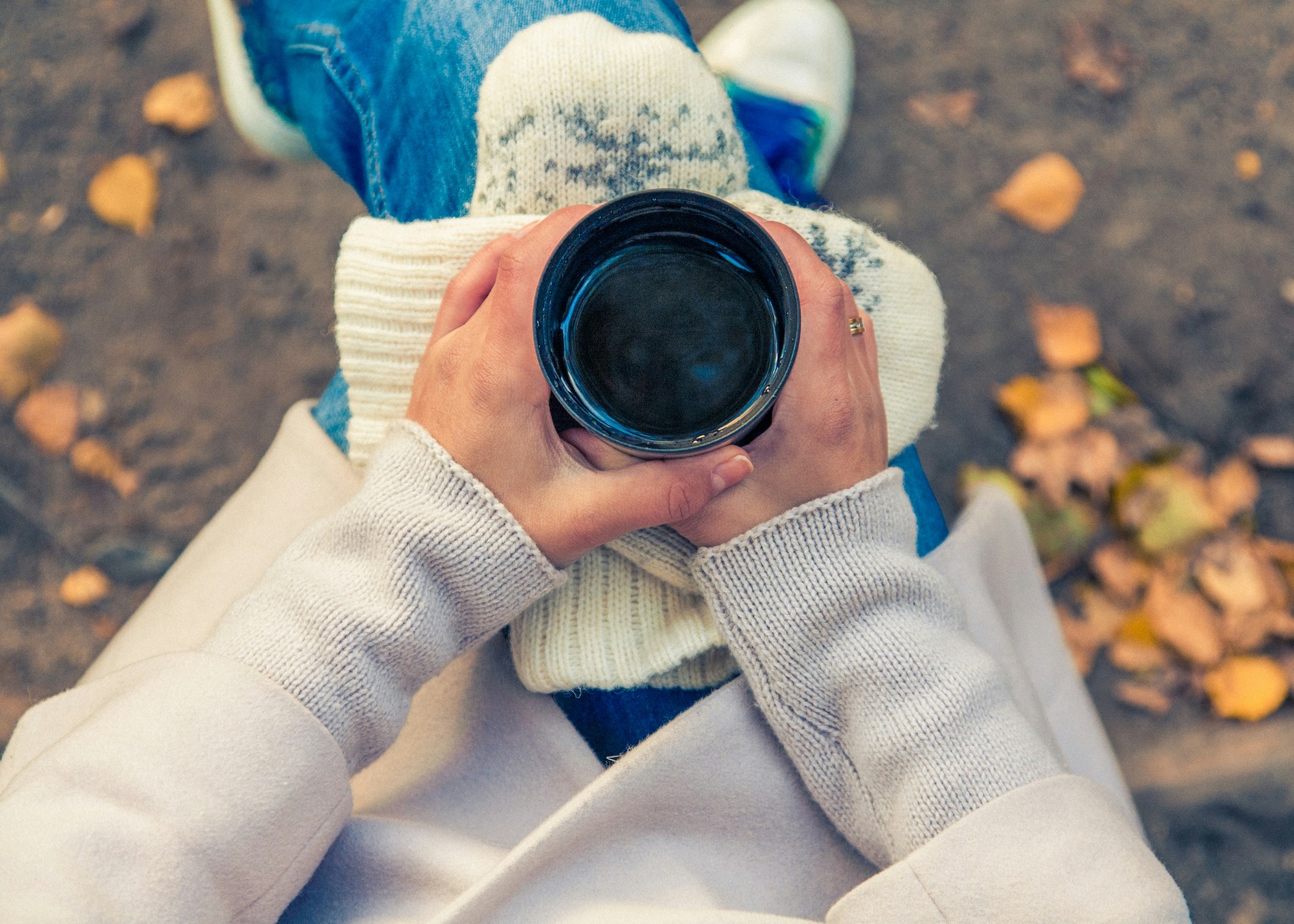 Woman holding coffee cup in the fall