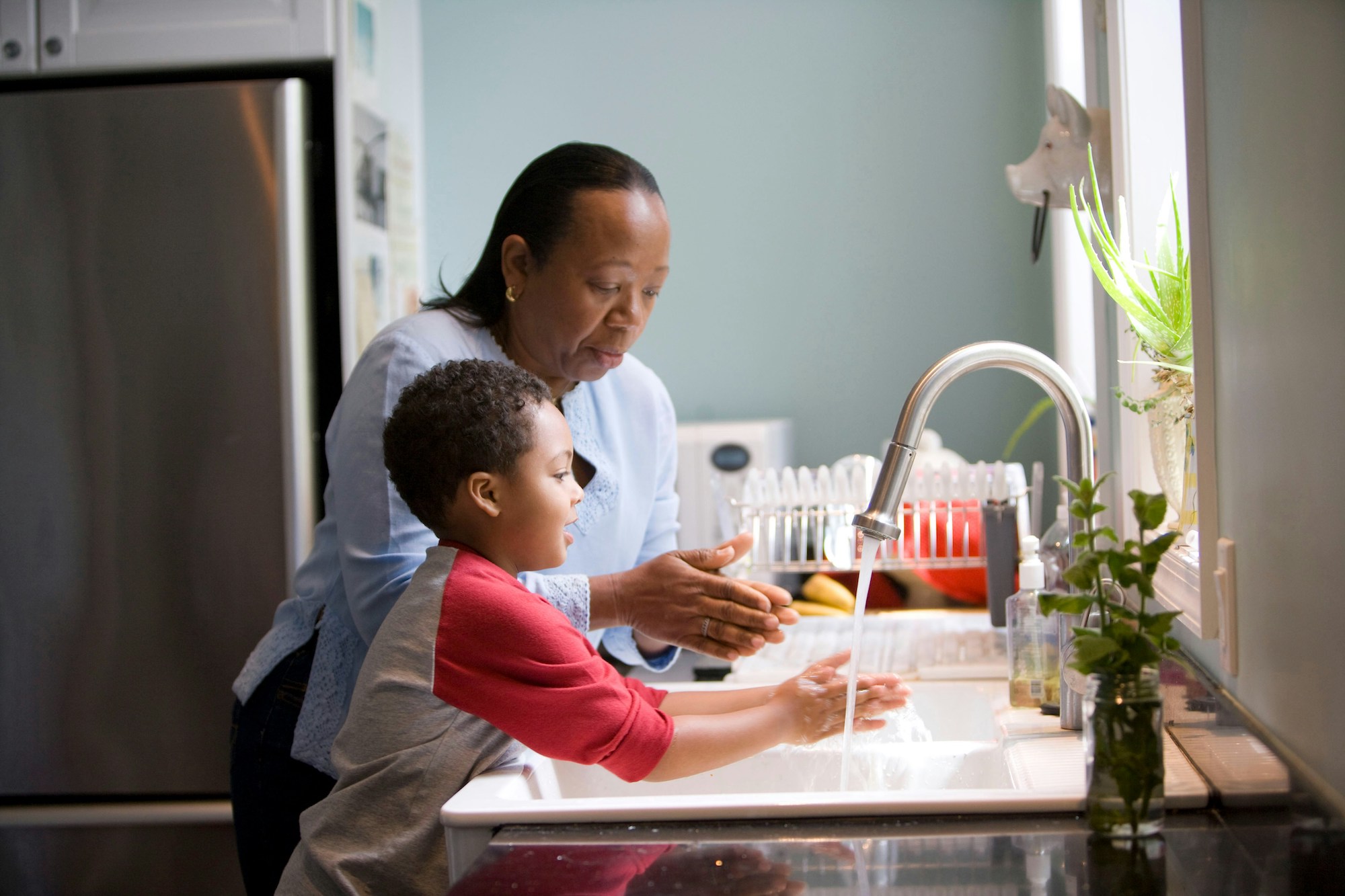 Grandma washing dishes with grandson