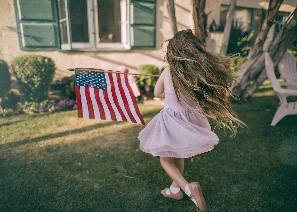 Young girl waving around American flag