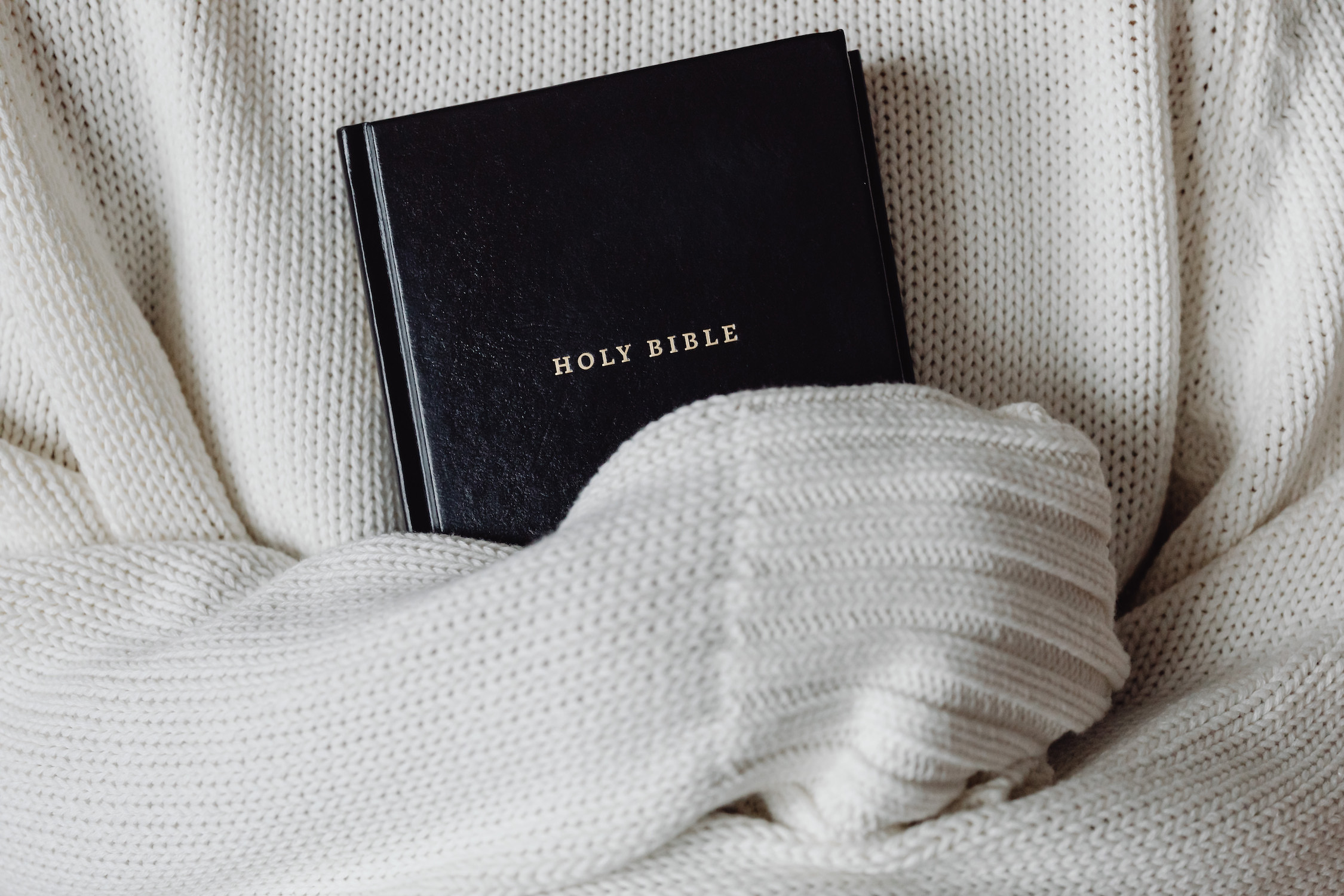 Woman in white sweater holding Bible