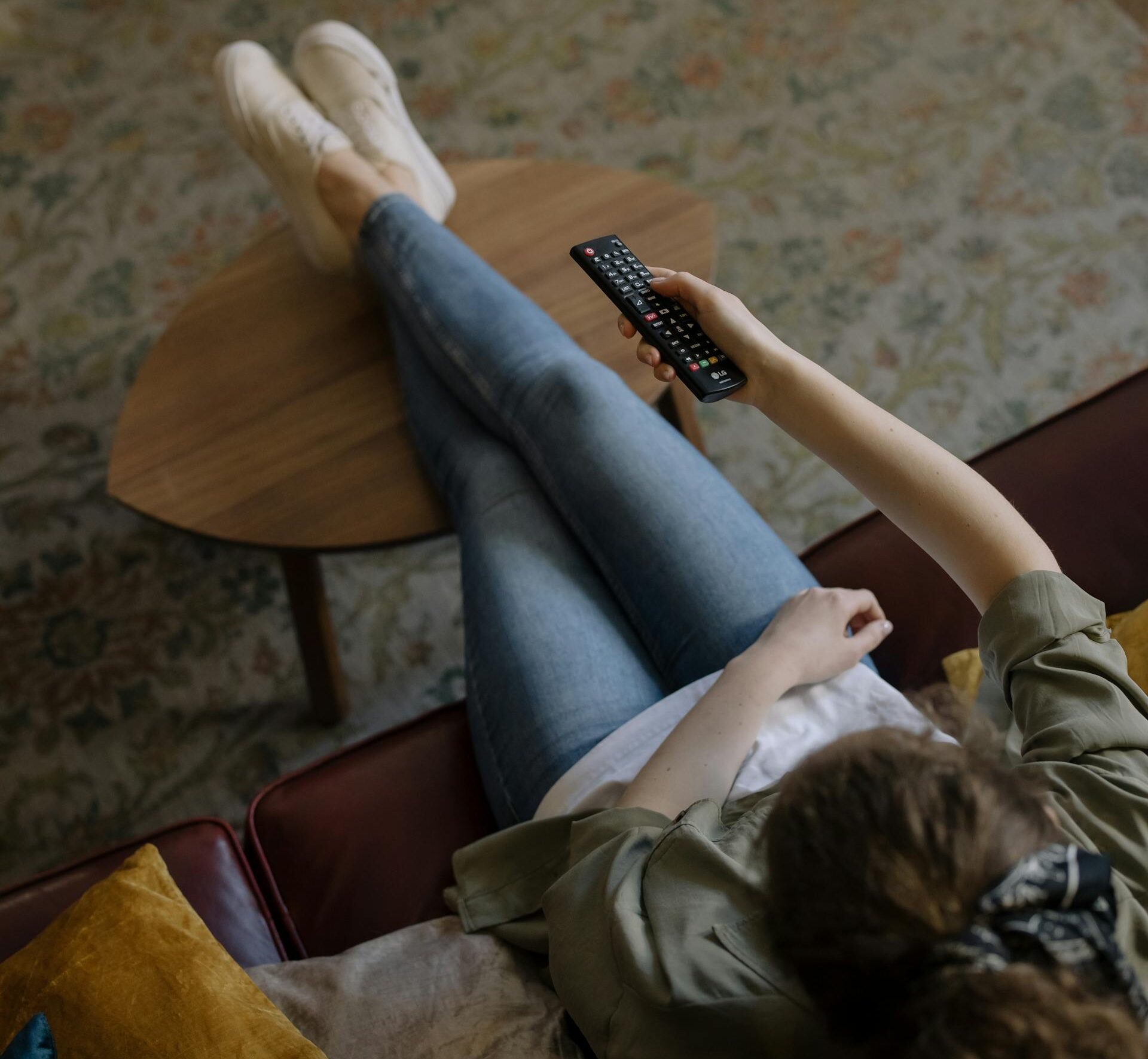 Woman in Brown T-shirt and Blue Denim Jeans Sitting on Brown Wooden Chair