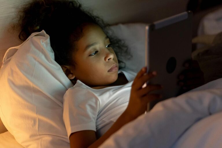 Christian Parenting and Screen Time: Girl sitting in bed playing on ipad