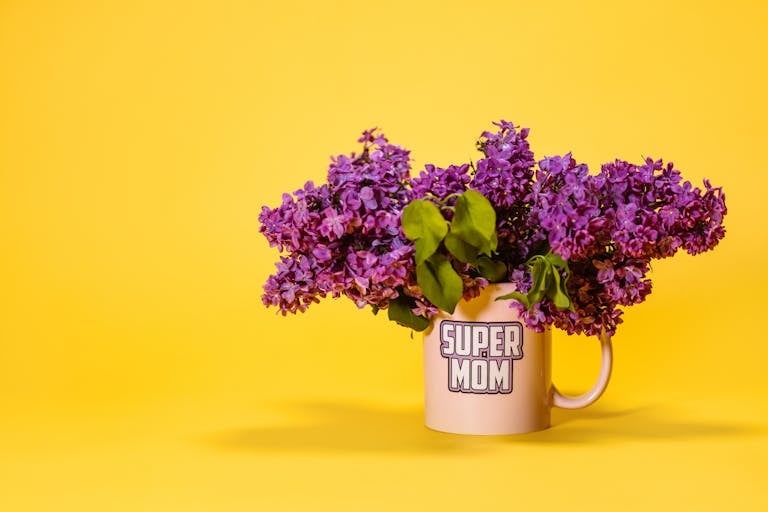 Single mom mother's day - A vibrant display of purple lilacs in a 'Super Mom' mug against a bright yellow backdrop, perfect for motherhood themes.