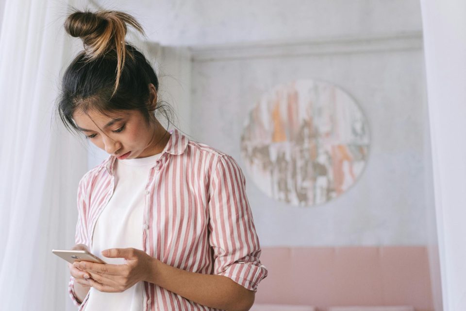 Woman in pink shirt scrolling phone when comparison steals your joy