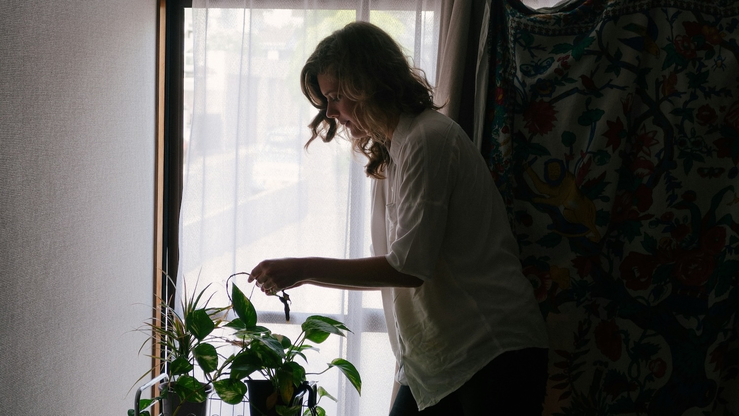 Woman in shadows watering plants and creating household systems